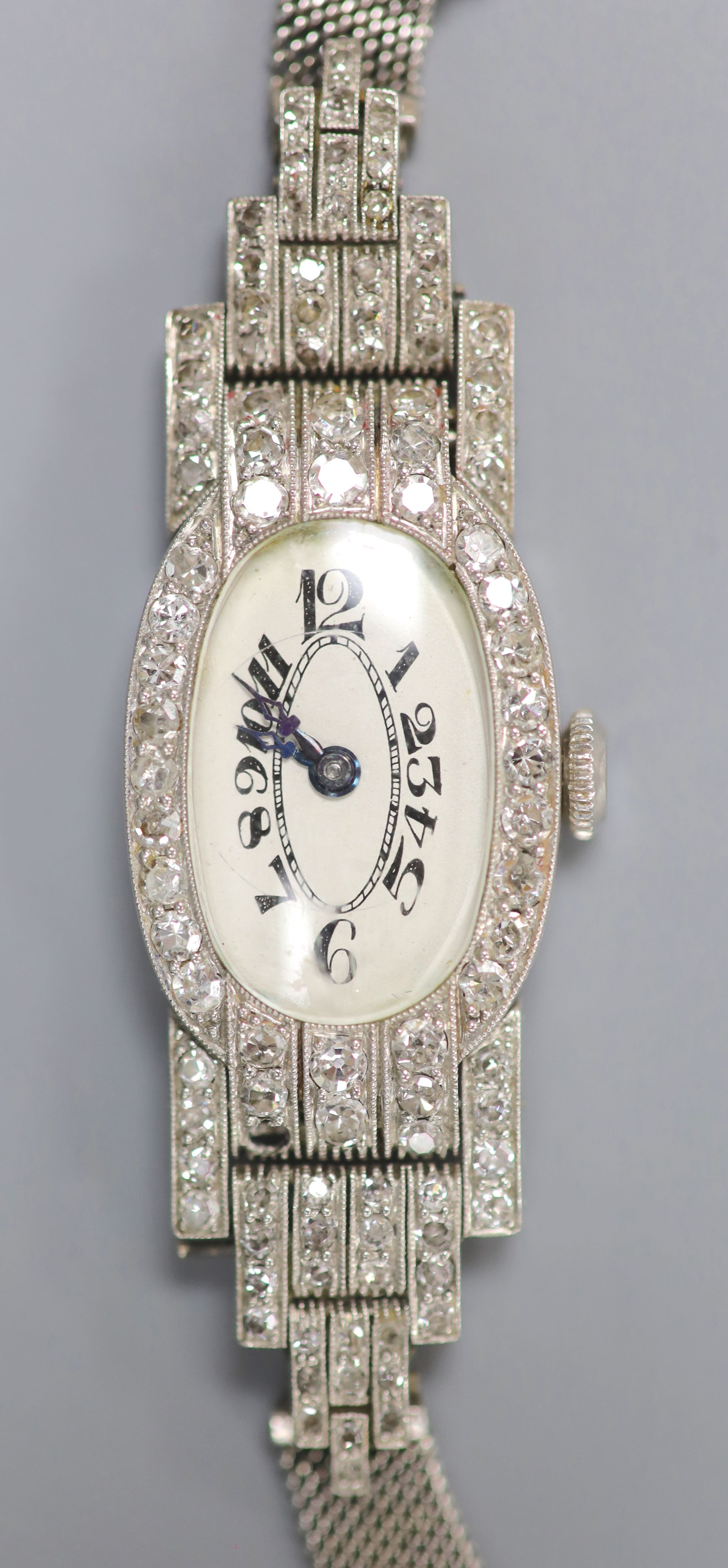 A lady's mid 20th century white metal (stamped platinum) and diamond set cocktail watch, with tumbling numerals, on an 18ct mesh link strap